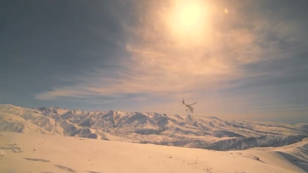 Hubschrauber fliegt vor dem Hintergrund von Schneebergen und Sonnenuntergang — Stockvideo