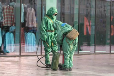 Biyolojik virüs korumalı giysiler giyen insanlar. 2019, COVID-19, Coronavirus hastalığına karşı önlem olarak halka açık bir yerde dezenfekte ve arındırma.