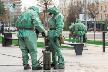 COVID-19 salgını. Biyolojik virüs koruyucu giysiler giyen iki tıp çalışanı koronavirüsten dezenfeksiyon için kimyasal püskürtüyorlar..