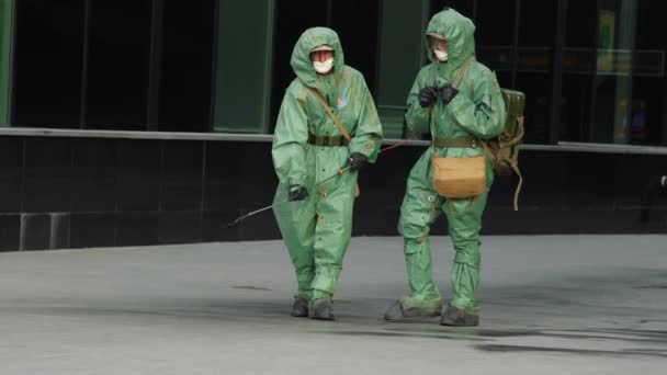 CHINA, MARCH 25, 2020: COVID-19 outbreak. Two medical workers in bio viral hazard protective suits spray of chemicals for disinfection from coronavirus. UltraHD 4K — Stock Video