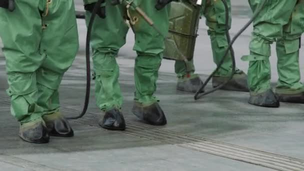 Militares em fatos protetores de risco biológico desinfetam a rua contra o coronavírus. Equipa de desinfecção em fatos de protecção a funcionar. UltraHD 4K — Vídeo de Stock