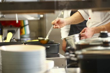 Şef mutfakta pilav pişirip karıştırıyor. Aşçıbaşıyla