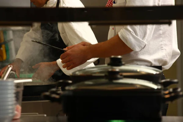 Cocinero profesional en la cocina preparando alimentos para los clientes que muestran —  Fotos de Stock