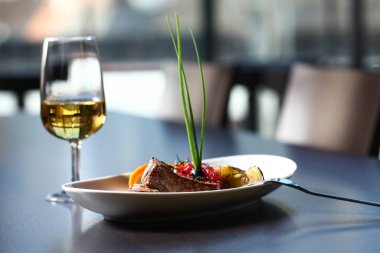 Arka planda bir bardak şarap ve sandalyeyle güzel bir yemek.