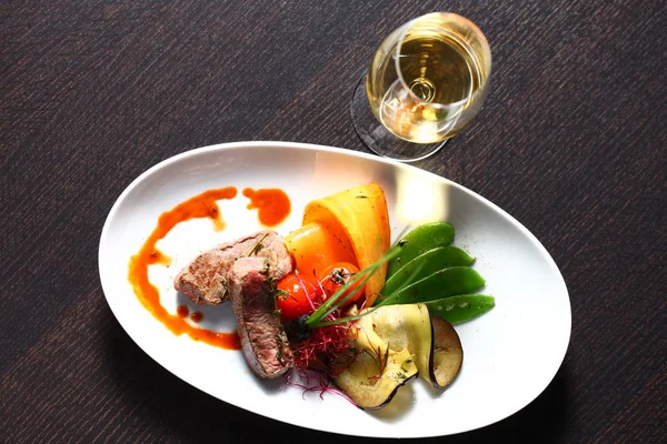 Sabrosa comida en la mesa en el restaurante con espacio para copias y platos ovalados y una copa de vino — Foto de Stock