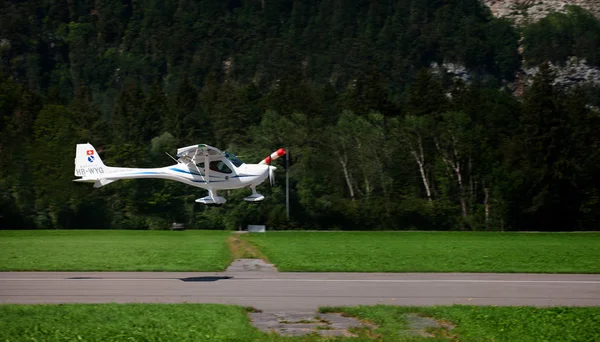 small airplane landing on a landing strip near forrest