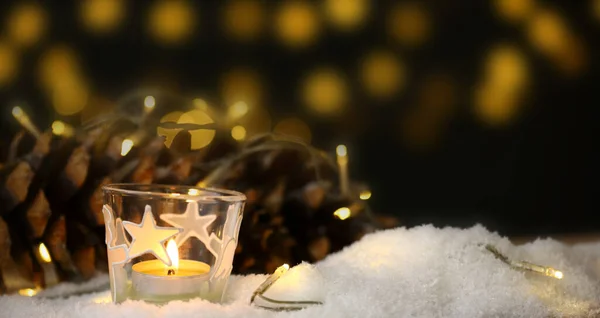 Tema de Navidad con velas, nieve, cono de pino y luz de Navidad — Foto de Stock