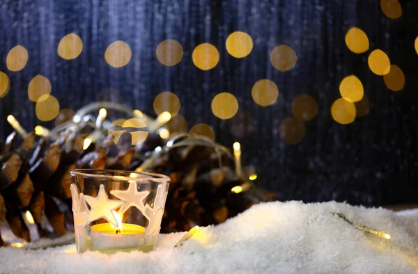 Tema de Navidad con velas, nieve, cono de pino y luz de Navidad — Foto de Stock