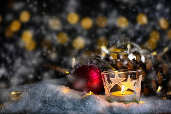 Tema de Navidad con velas, nieve, cono de pino y luz de Navidad — Foto de Stock