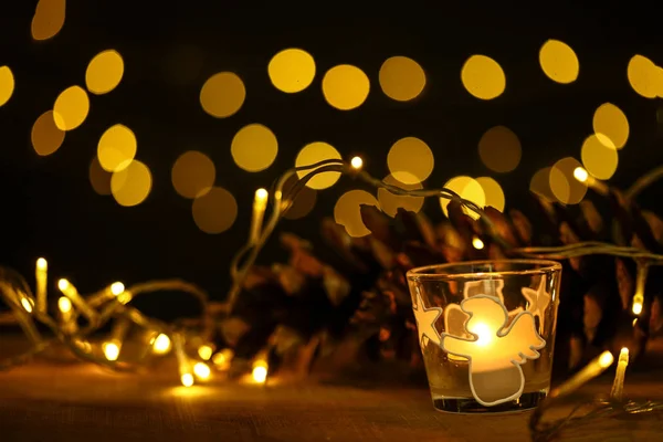 Tema de Navidad con velas, nieve, cono de pino y luz de Navidad — Foto de Stock