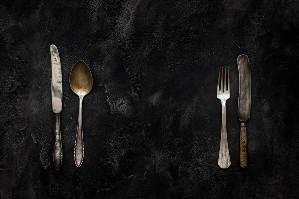 Старый гранж-нож, ложка и вилка на бетоне вид сверху

