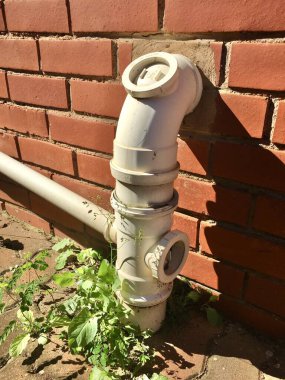 Dışarıdaki tesisat borusunda kırmızı tuğla duvarda yabani otları çevreleyen