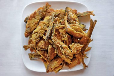 Beyaz arka planda beyaz bir tabakta kızarmış balık levreği. Ev yemeği. Üst Manzara. Yatay.