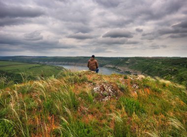Kayadaki turist. Bir adam güzel bir nehrin kanyonunda duruyor.