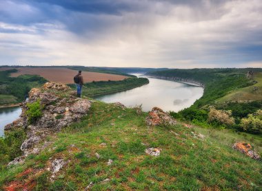 Kayadaki turist. Bir adam güzel bir nehrin kanyonunda duruyor.