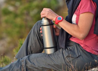 Termoslu bir turist. Kadın doğaya çay döker. Kayadaki kız.