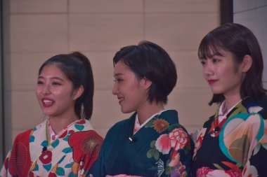 three japanese woman in typical clothes smiling at camera