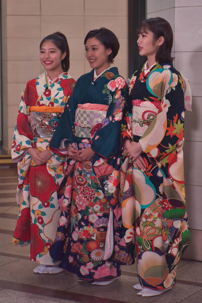 three japanese woman in typical clothes smiling at camera