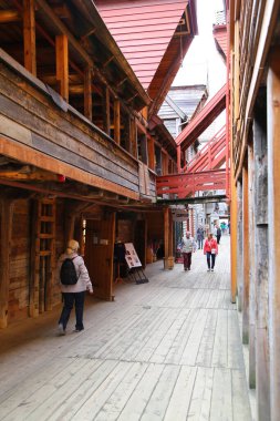 Bergen, Norveç 'in ünlü simgesi, renkli cepheleriyle Hanseatik Lig evleri ve dükkanlar boyunca yürüyen insanlar.