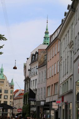 Kopenhag 'ın göbeğindeki Amagertorv alışveriş bölgesindeki Leylek Çeşmesi' nin etrafındaki sokakta gün ışığının tadını çıkaran müşteriler ve turistler.