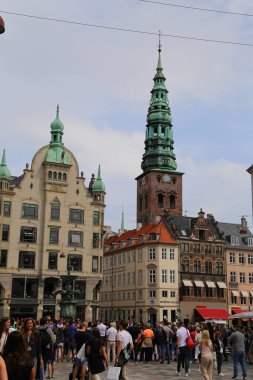 Kopenhag 'ın göbeğindeki Amagertorv alışveriş bölgesindeki Leylek Çeşmesi' nin etrafındaki sokakta gün ışığının tadını çıkaran müşteriler ve turistler.