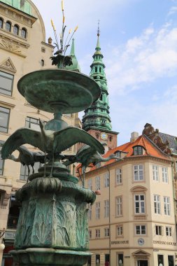 Kopenhag 'ın göbeğindeki Amagertorv alışveriş bölgesindeki Leylek Çeşmesi' nin etrafındaki sokakta gün ışığının tadını çıkaran müşteriler ve turistler.
