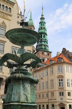 Kopenhag 'ın göbeğindeki Amagertorv alışveriş bölgesindeki Leylek Çeşmesi' nin etrafındaki sokakta gün ışığının tadını çıkaran müşteriler ve turistler.
