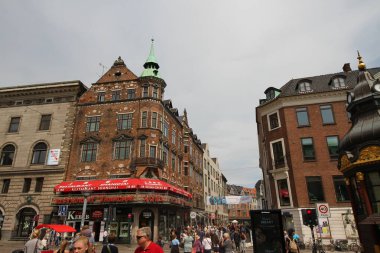 Kopenhag 'ın göbeğindeki Amagertorv alışveriş bölgesindeki Leylek Çeşmesi' nin etrafındaki sokakta gün ışığının tadını çıkaran müşteriler ve turistler.