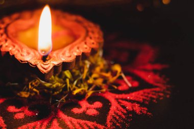 Diwali 'de kırmızı Rangoli tasarımı ve flo ile güzel bir toprak lambası.