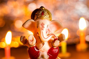 Tanrı Ganesha heykeli ve arkasında mumlar olan ışık festivali.