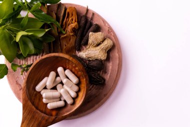 Tahta spatula ve düz taş yüzeyde yeşil yapraklı bitkisel ilaçlarla çeşitli Hint baharatlarının yakın görüntüsü. Bitkisel ve alternatif tıp kavramları