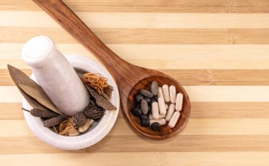 Beyaz havan topuzunda farklı baharatların yakın çekimi ve tahta arka planda tahta kaşıkta ayurvedik ilaçlar.
