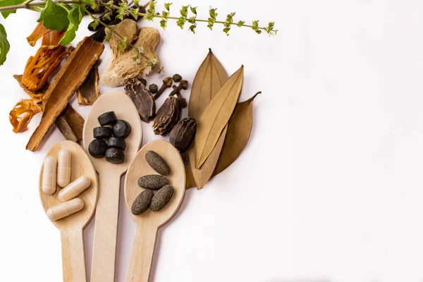 Beyaz arka planda yeşil oktav ya da tül yapraklı ahşap kaşıkta farklı baharat ve ayurvedic ilaç koleksiyonu. Ayurvedic tıp konsepti