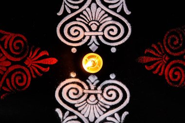 Parlayan güzel bir diya ve siyah arka planda kırmızı beyaz rangoli sanatının en üst görüntüsü. diwali konsepti