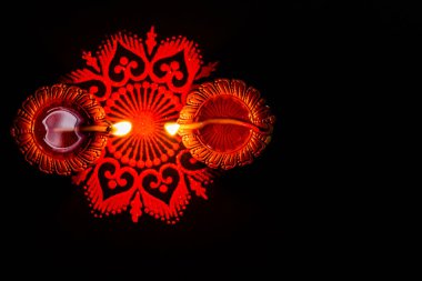 İki parıldayan terracotta lambası ve siyah arka plana karşı rangoli. diwali concpet