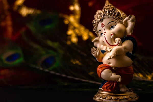 Zamazane Czerwone Złote Tło Pawim Piórem Posągiem Ganesha Pierwszym Planie — Zdjęcie stockowe