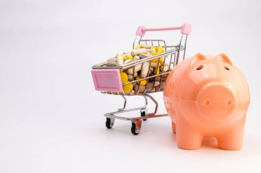 İlaçlar el arabasında. İlaç ve ilaç dolu alışveriş arabası. İlaç alıyorum. Piggybank ve para kulesi eczacılık maliyet kavramını kapat.