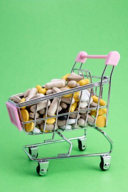 Yeşil arka planda alışveriş arabası. Ücretli ilaç. İlaç satın alma