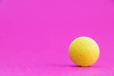 Pembe arka planda, kırpma yolu ile izole edilmiş sarı hap. İlaç ve eczane kavramı