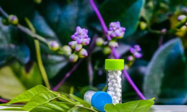 Yeşil arka planda iki Homeopati ilaç şişesinin yakın plan çekimi.