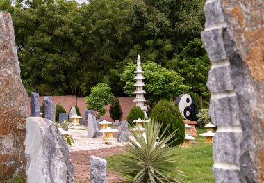 Arka planda taşralı kayalar ve sık ağaçlar olan bir parkta Yin Yang metal yapısı. Zen ve Budizm kavramı