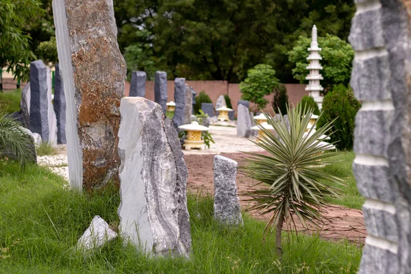 Weathered brown rocks with worn out surface and ornamental plants in an outdoor park. Zen concept