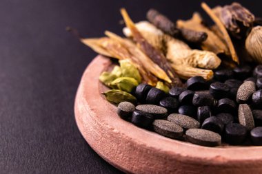  Siyah arka planda baharatlarla dolu bitkisel haplar ve tabletler, ayurveda konsepti.