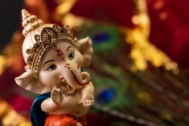 Yüksek açılı Ganpati heykelinin arka plandaki bulanık kırmızı altın ve tavus kuşu tüyüne yakın plan fotokopi alanı ile. din kavramı