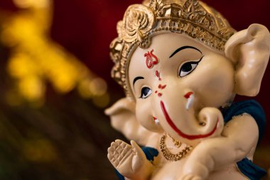 Kutsanmış güzel Ganesha heykelinin makro yakın çekim görüntüsü bulanık ve altın arka plana karşı. din ve Hindu kavramı