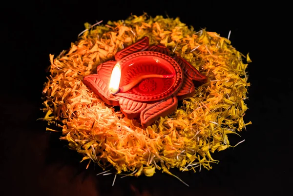 각도에서 빛나는 테라코타 램프를 어두운 꽃잎에 올렸습니다 신앙의 — 스톡 사진