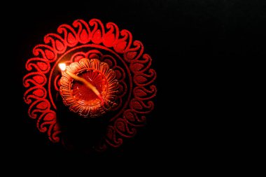 Diwali 'de kırmızı Rangoli tasarımı ve çiçekleri olan güzel bir toprak lambası. Diwali konsepti