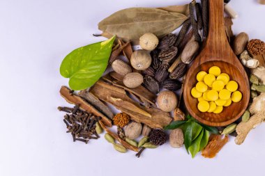 Ayurvedic tıp konsepti. Tahta kaşıkta Ayurvedic haplar ve beyaz arka planda baharatlar