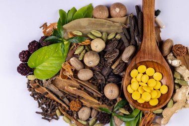 Bitkisel tedavi konsepti. Tahta kaşıkta Ayurvedic ilaçlar ve beyaz arka planda baharatlar