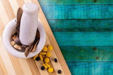 Arka planda mavi çizgili ahşap kesim tahtası ve toz için kurutulmuş otlar içeren havan topu. Ayurveda kavramı